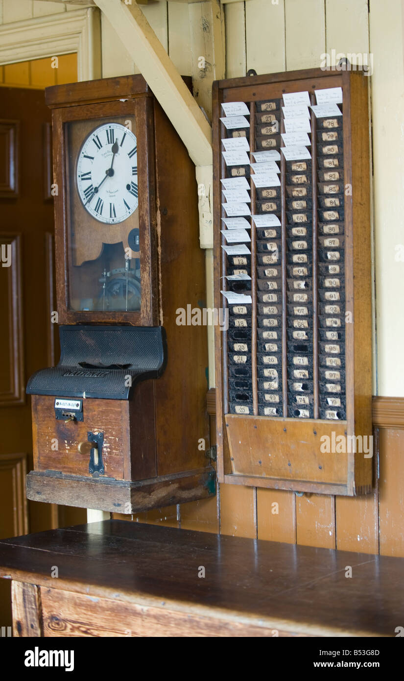 Clocking sulla macchina e schede di tempo sulla parete di fabbrica Foto Stock