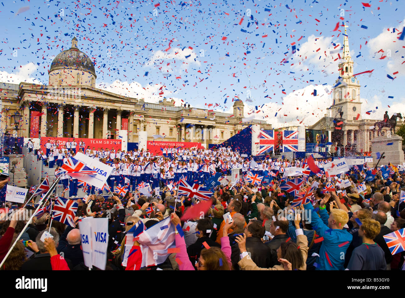 Le Olimpiadi del 2008 eroi parade Team GB UK London Trafalgar Square folla & atleti celebrare red white & blue coriandoli Union Jack flag bandiere blu cielo Foto Stock