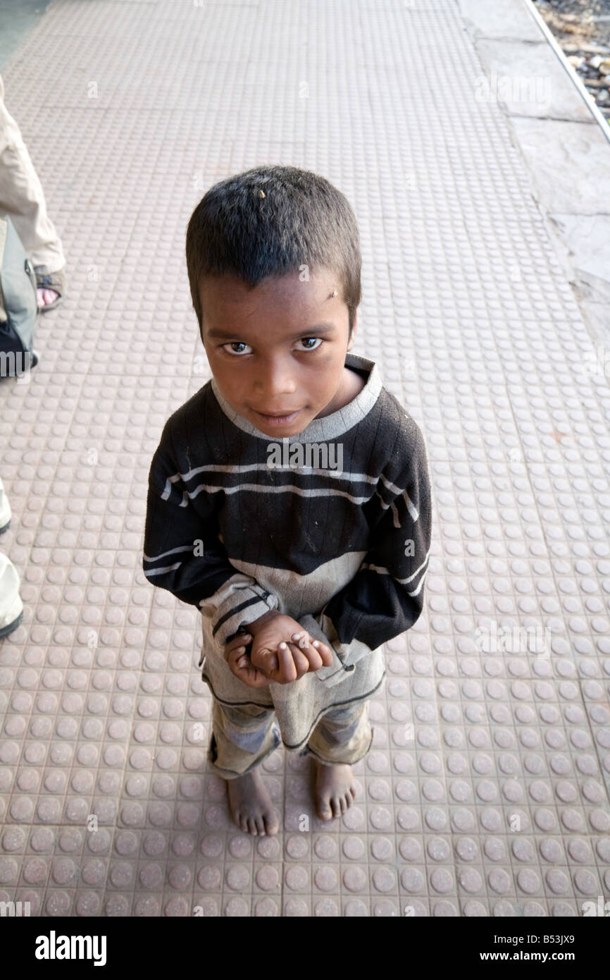 Un giovane ragazzo di elemosinare sulla piattaforma, Sawai Madhopur stazione, Rajasthan, India Foto Stock