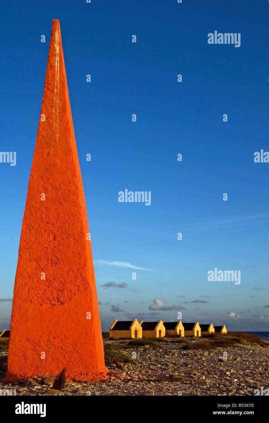 Red obelisco e capanne slave nella luce della sera vicino al solar saline su Bonaire, Antille olandesi nei Caraibi Foto Stock