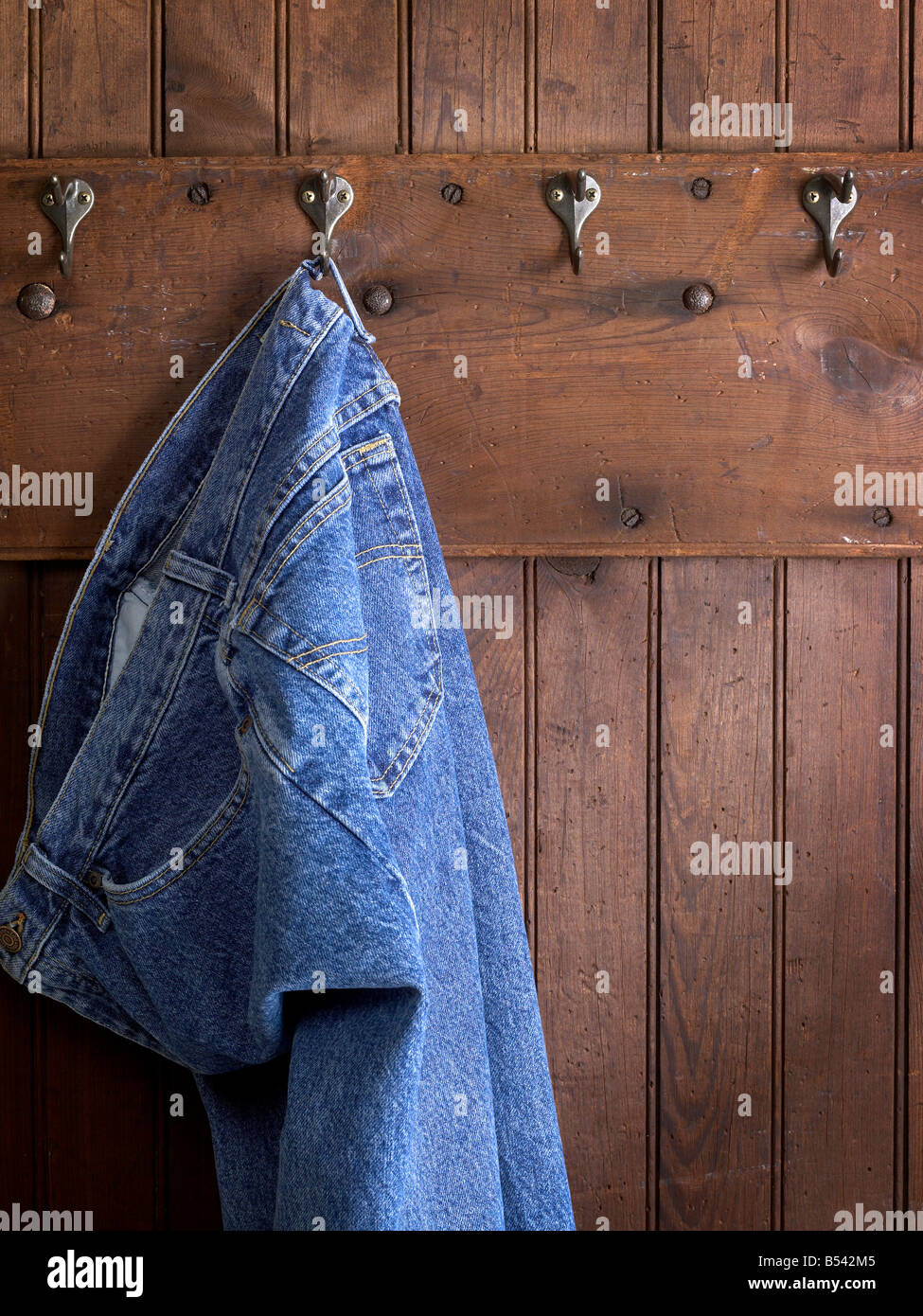 Jeans blu appesa al gancio alterò la parete in legno Foto Stock