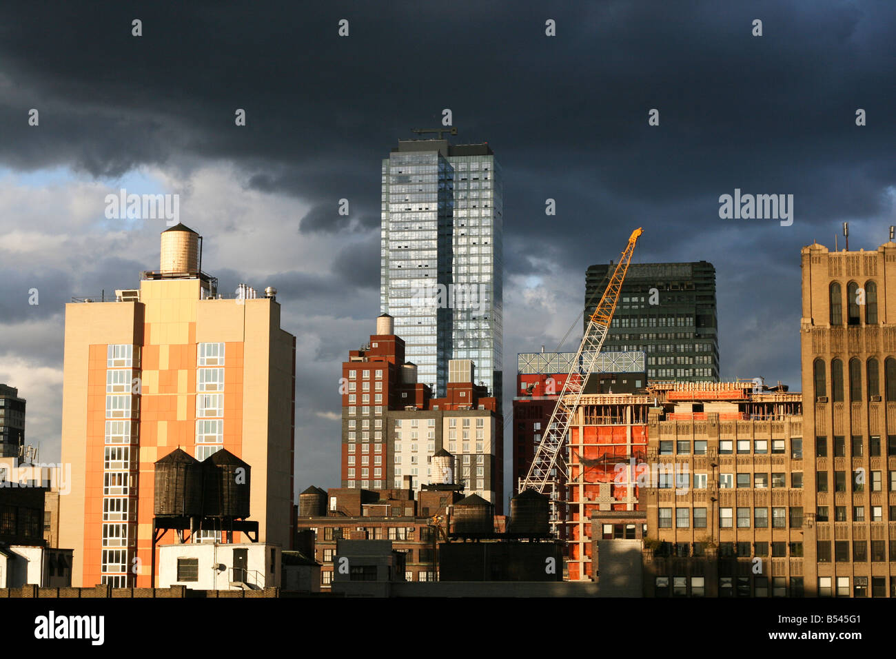 Dark Cloud incombenti sulla skyline di New York con la gru che mostra la crescita e industrializzazione Foto Stock