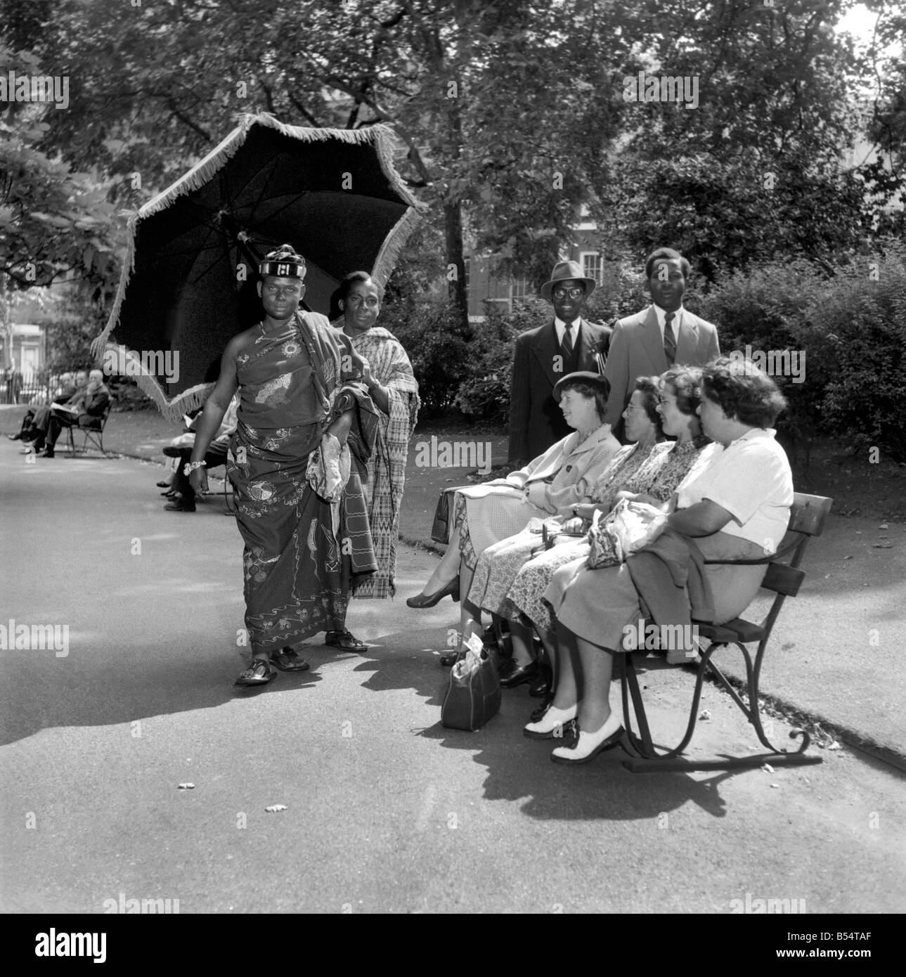 Gold Coast Chief visite di Londra. Il capo di Nana Kwabena Kenh II della Gold Coast e realizzato una pittoresca vista quando ha passeggiato in Lincolns nei campi con un operatore in seguito a ridosso tenendo un grande ombrello per tenere fuori il sole. Il capo è di andare a una conferenza a Cambridge. Agosto 1953 D5096-001 Foto Stock