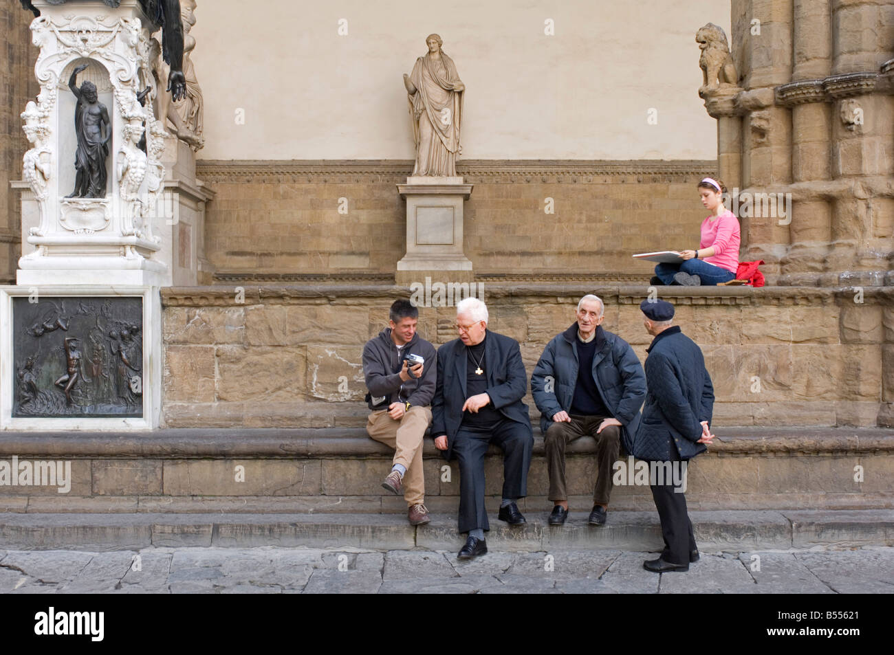 Un gruppo di uomini chat mentre un artista dipinge dalla Loggia dei Lanzi gallery in Piazza della Signoria a Firenze. Foto Stock