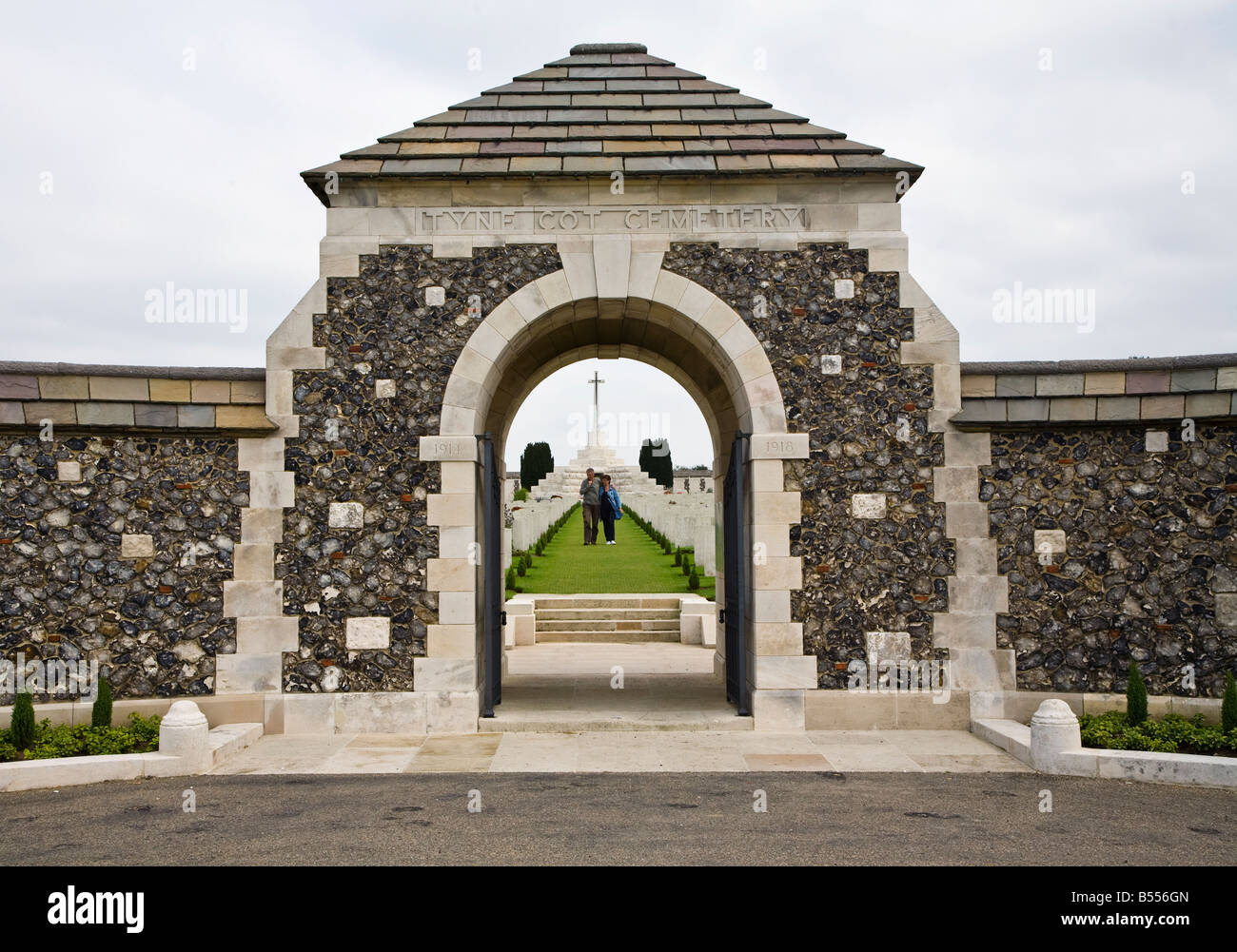 Due persone che camminano tra tombe all'ingresso Tyne Cot British War Memorial Cemetery Belgio Foto Stock