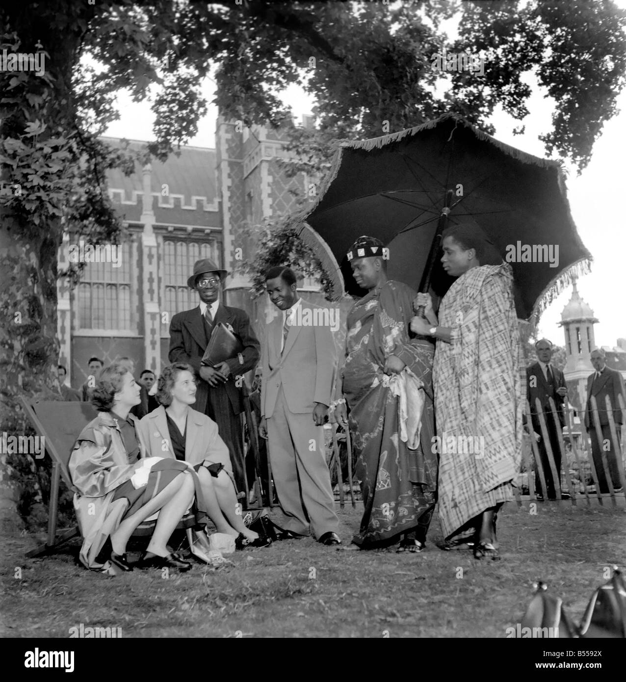 Gold Coast Chief visite di Londra. Il capo di Nana Kwabena Kenh II della Gold Coast e realizzato una pittoresca vista quando ha passeggiato in Lincolns nei campi con un operatore in seguito a ridosso tenendo un grande ombrello per tenere fuori il sole. Il capo è di andare a una conferenza a Cambridge. Agosto 1953 D5096 Foto Stock