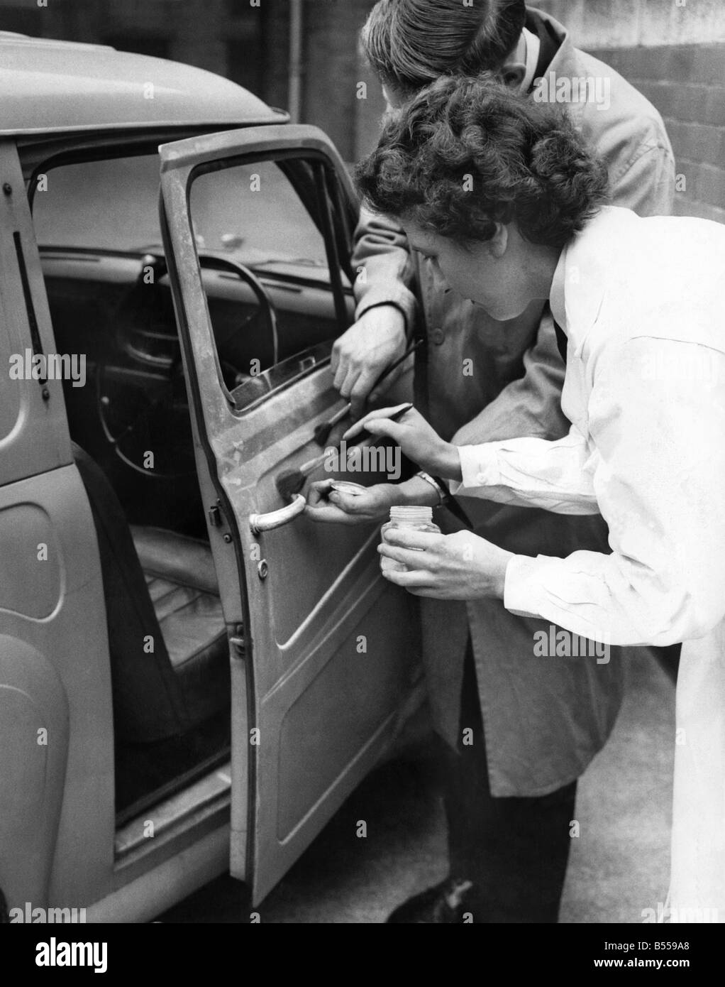 Un furto di auto si schianta contro una parete ed è abbandonato. Finger Print esperti sono chiamati a e qui la polizia-donna Gwendoline Marsh e Cadet Roger Dunkerley utilizzare pennelli e polvere per raccogliere le stampe. Maggio 1959 P011331 Foto Stock