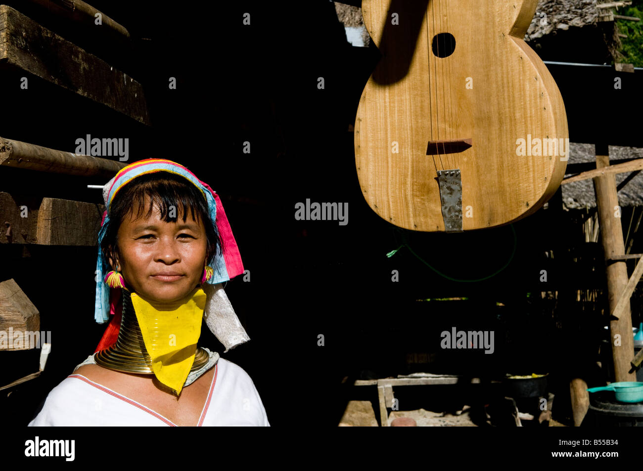 Ritratto di un Padong lungo collo donna sorge nei pressi di un tradizionale strumento a corda Foto Stock