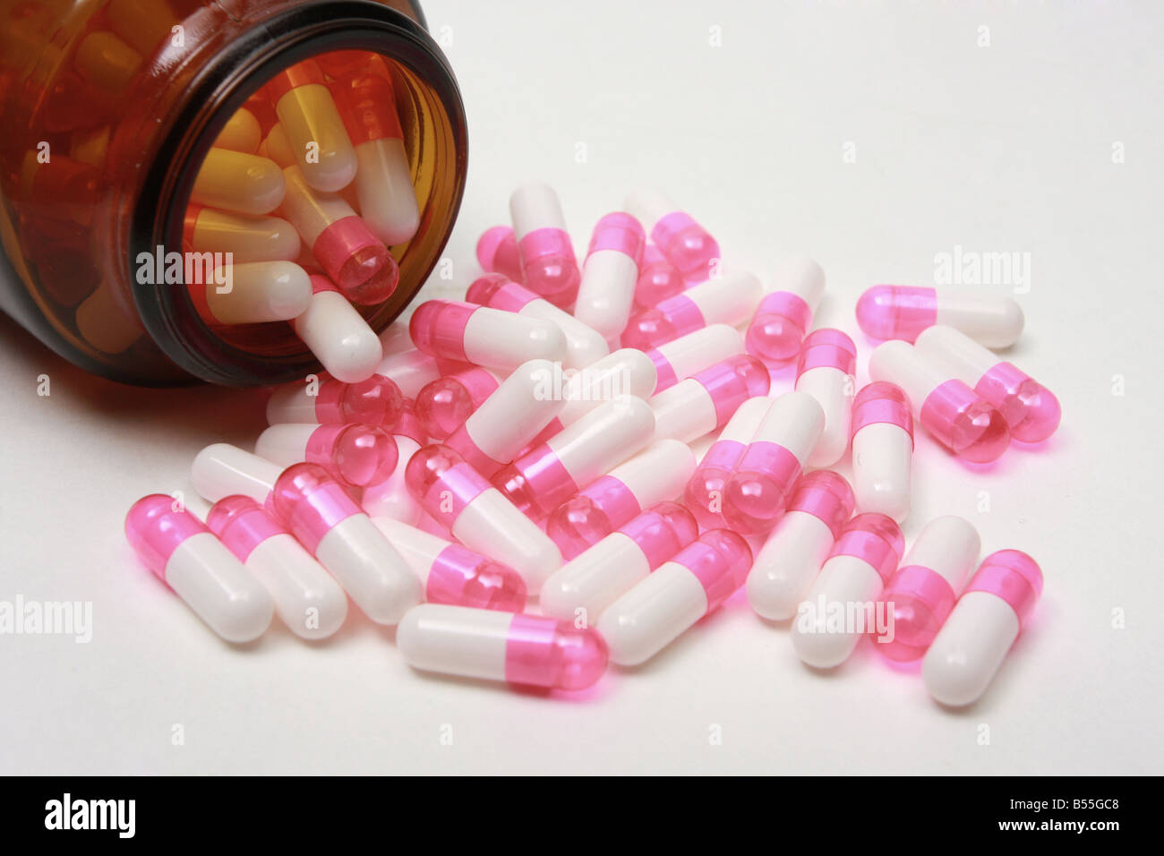 Pillole di farmaco riversando fuori di una pillola bottiglia su bianco Foto Stock