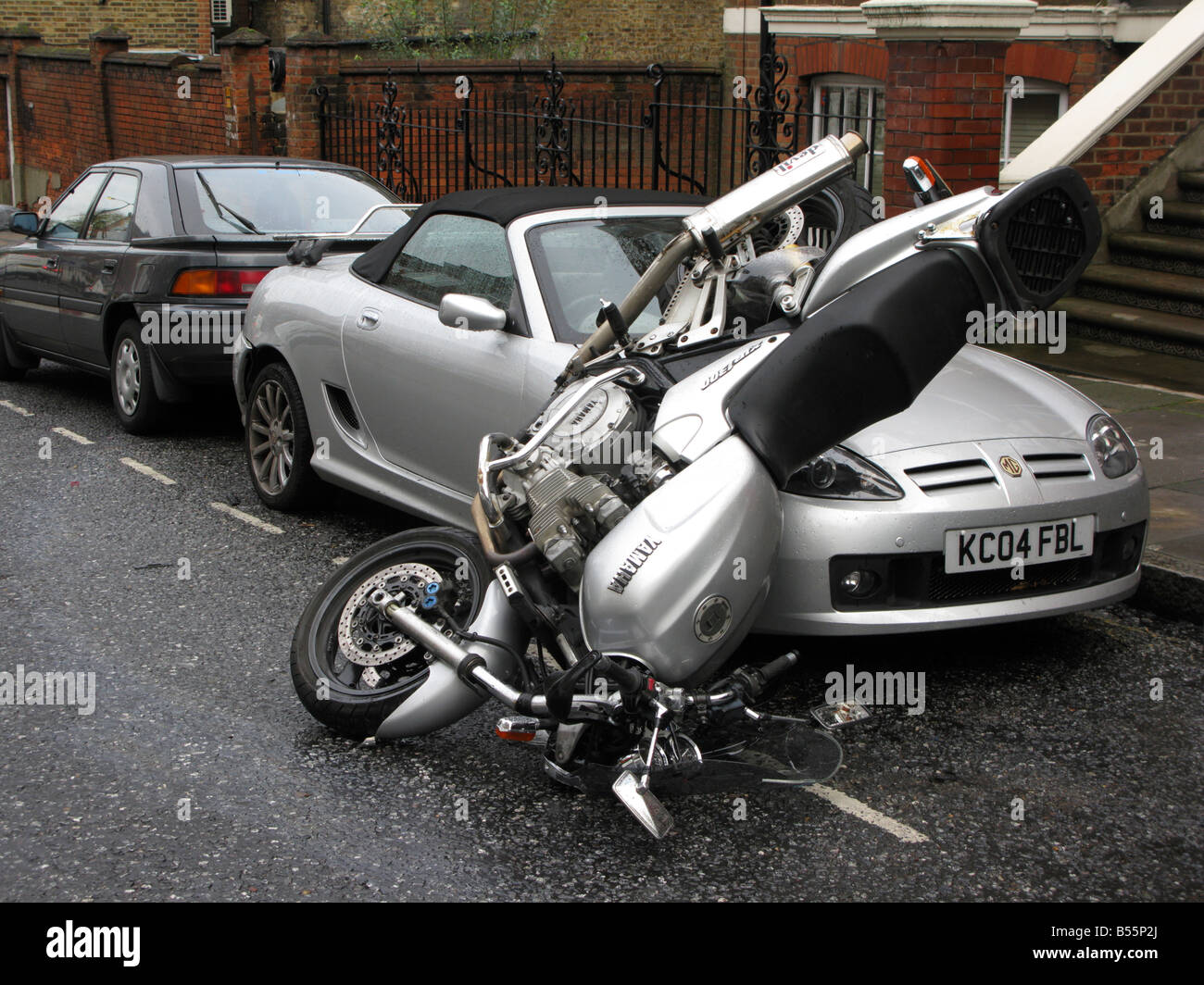 Un incidente motociclistico con moto di atterraggio su auto del cofano Foto Stock
