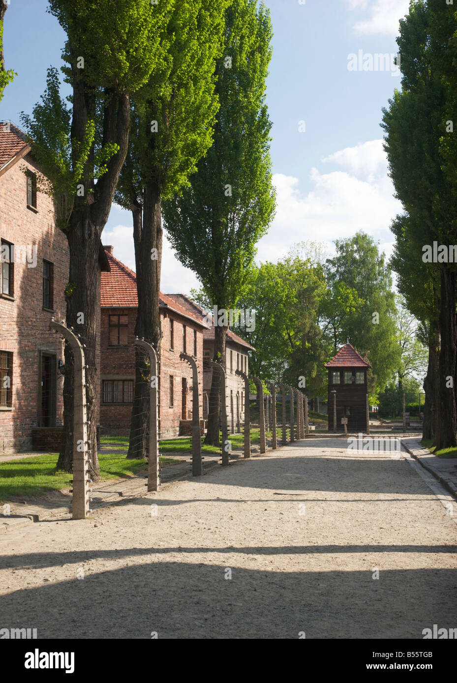 Alley con edifici in mattoni, una torre di guardia e i resti della recinzione elettrificata nell'ex campo di concentramento di Auschwitz ho Foto Stock