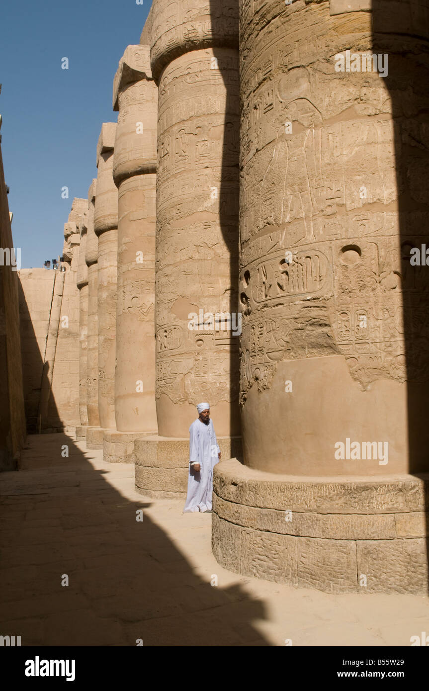 Un egiziano l uomo sta in mezzo alle colonne scolpite della grande Hypostyle Hall dal distretto di Amon-Ra, Tempio di Karnak complesso nei pressi di Luxor in Egitto Foto Stock