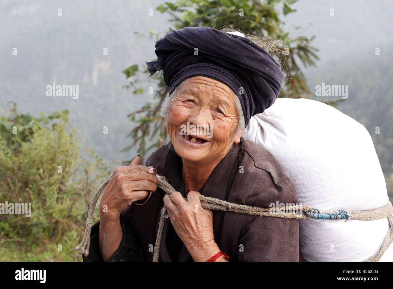 Anziani Miao Donna che cammina sulla strada di montagna nella provincia di Guizhou in Cina Foto Stock