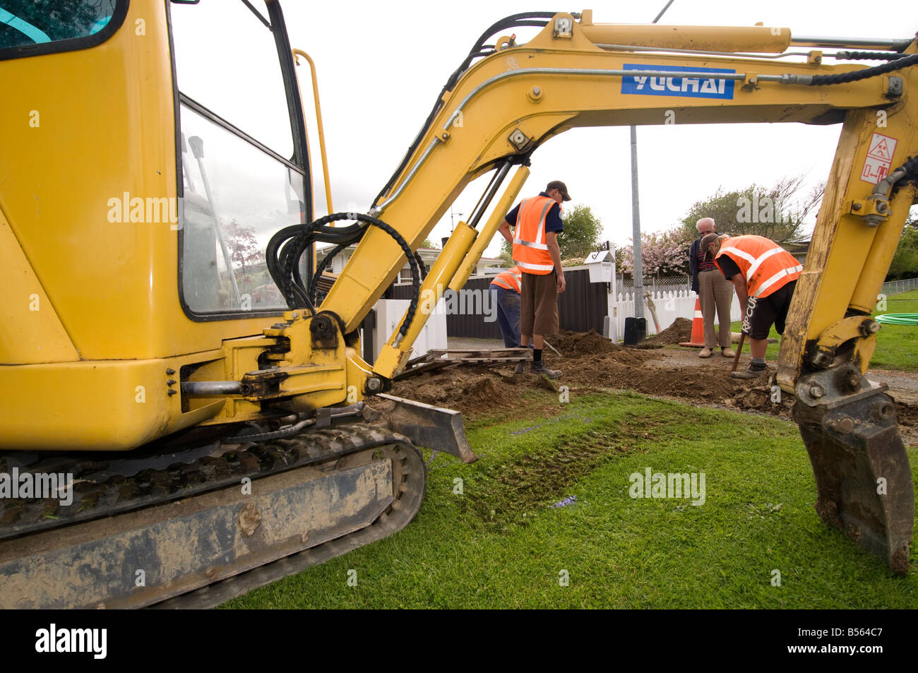 Gli uomini di scavare un buco per tubazioni di acqua frammed da digger Foto Stock