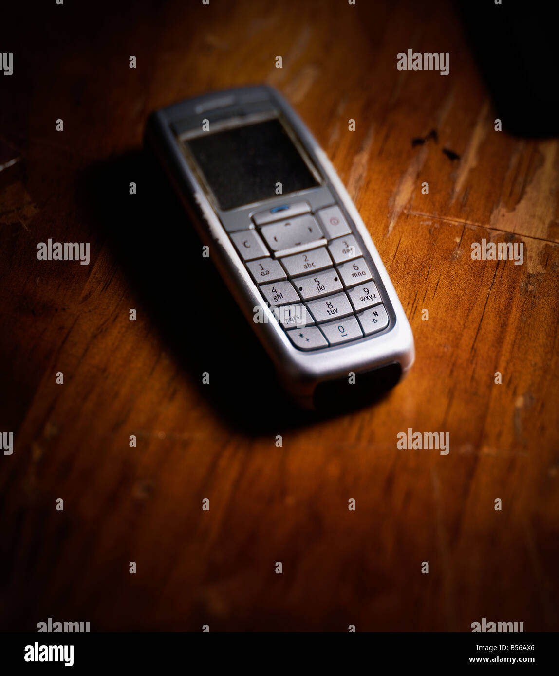 Moody fotografia di un vecchio telefono cellulare su un vecchio tavolo in legno Foto Stock