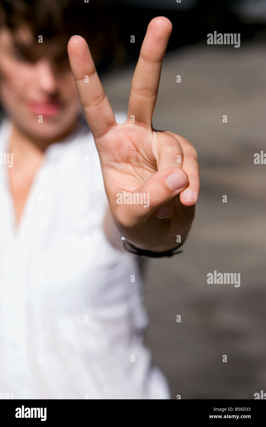 Una giovane donna che fa un segno di pace. Foto Stock