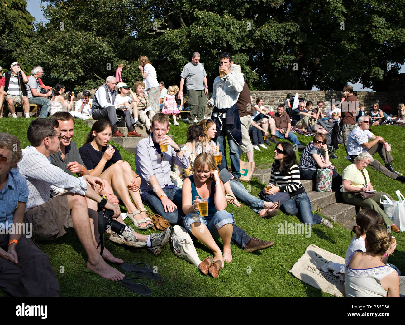 Le persone a bere birra seduti su erba a Abergavenny Food Festival Wales UK Foto Stock
