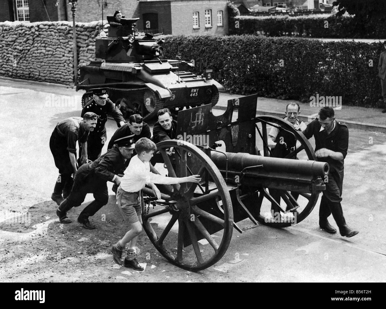 Un ricordo della Prima Guerra Mondiale, un obice tedesco essendo spinto verso il mucchio di rottami di metallo in un villaggio nel Surrey mentre una luce serbatoio passa da. ;Maggio 1945 ;P010150 Foto Stock