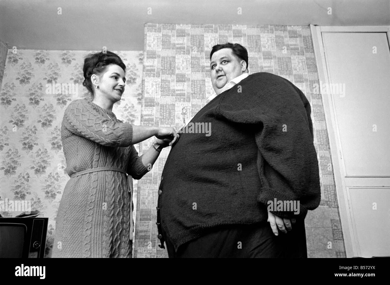 Mondo uomo Fattest: Sig.ra Gwen Matthewman raccordo 38-stone Arthur Armitage con il cardigan che ha avuto il suo 30 ore a lavorare a maglia per lui. Dicembre 1969 Z12233-004 Foto Stock