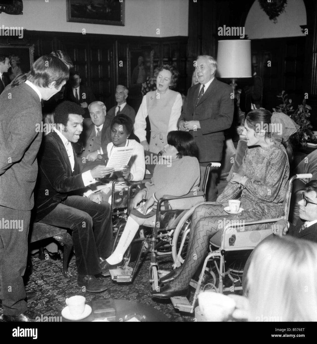 Il primo ministro Harold Wilson visto qui con la moglie Maria atttending a carol concerto di celebrità della televisione per i bambini disabili. Kenny Lynch è visto qui di eseguire per una giovane ragazza in una sedia a rotelle. Dicembre 1969 Z12414 Foto Stock