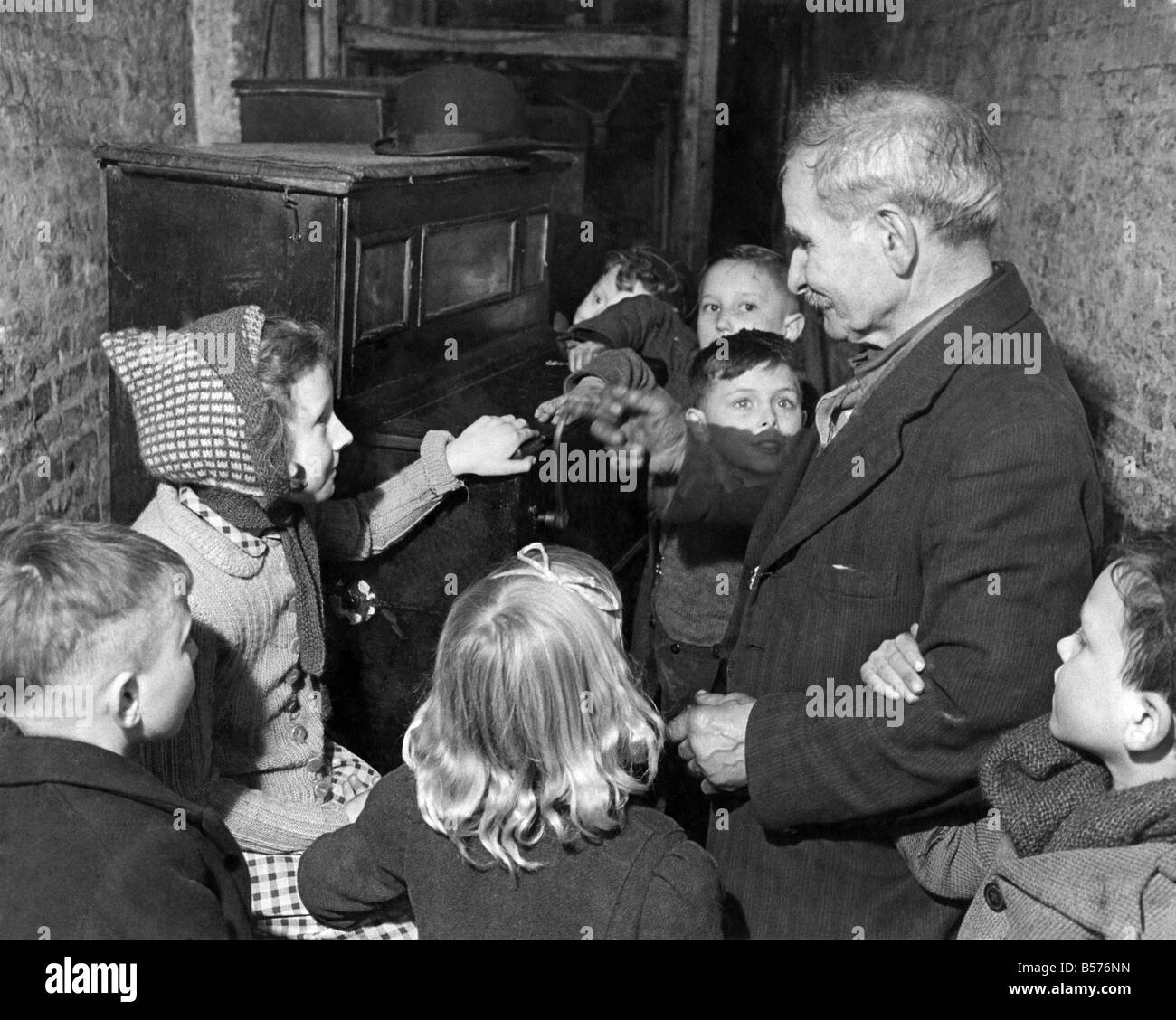 I bambini ascoltare un organetto essendo giocato. Febbraio 1944 P004919 Foto Stock