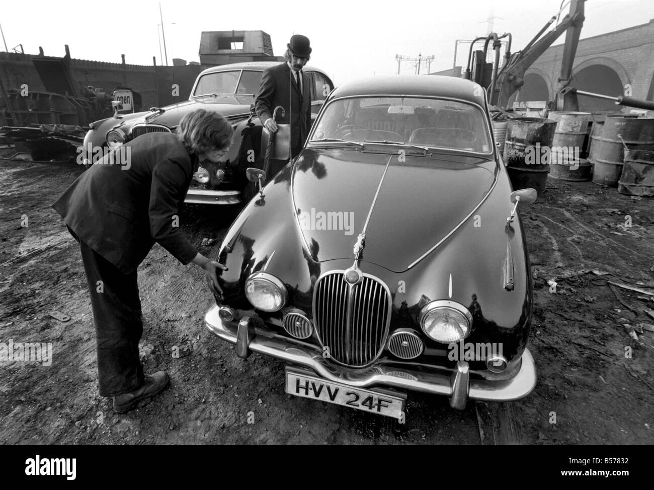 Insolito/Suit/Bowler cappello: Uomo sfridi Jaguar auto: D'altro canto, direttore delle vendite per il sig. Graham Parkes, chi dice che non può più permettersi di eseguire il suo 15 miglia per gallone Jaguar, e era disgustato presso i concessionari' offre, ha deciso di guardare la sua distruzione. Febbraio 1975 75-01164-002-001 Foto Stock
