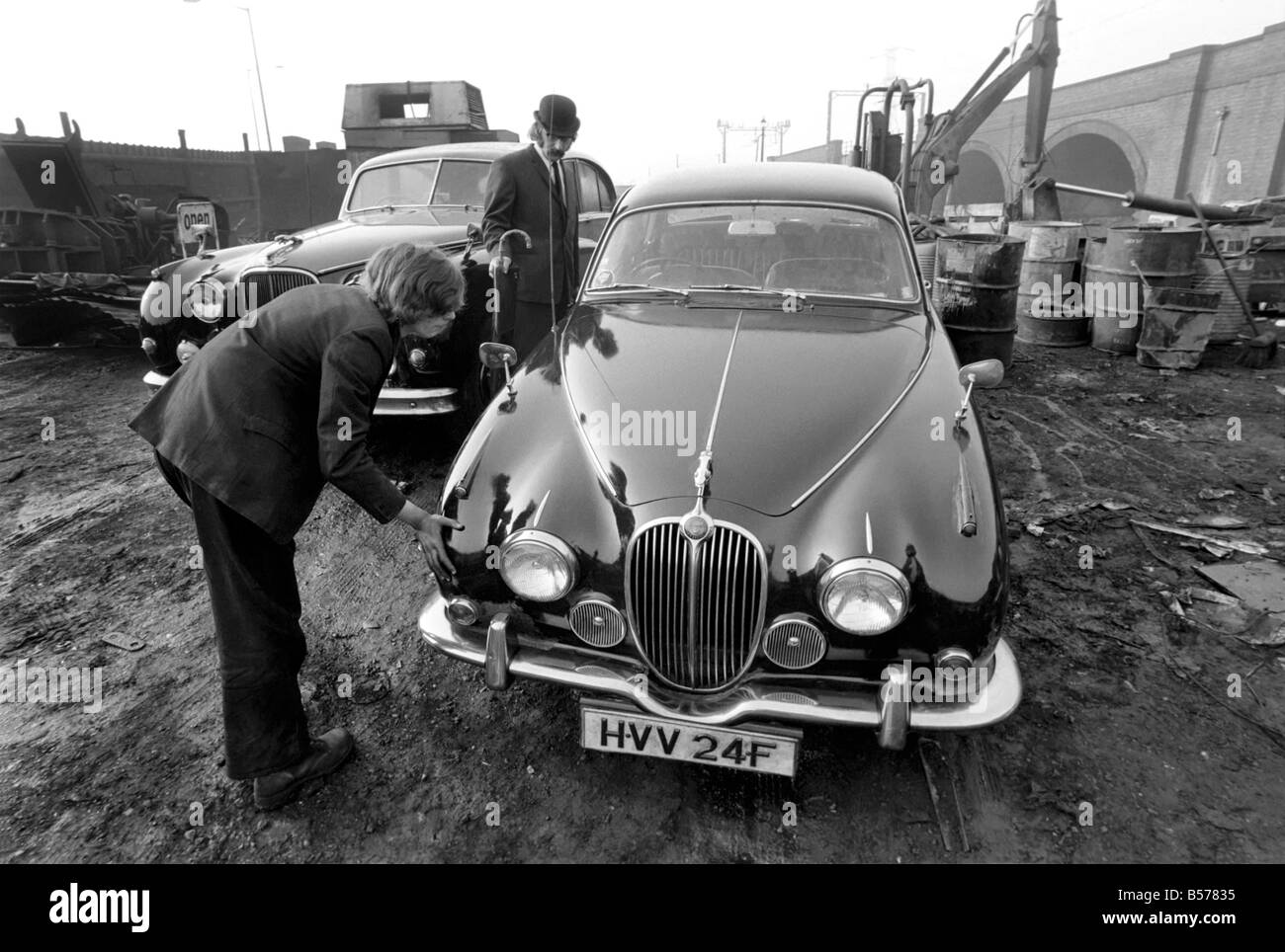 Insolito/Suit/Bowler cappello: Uomo sfridi Jaguar auto: D'altro canto, direttore delle vendite per il sig. Graham Parkes, chi dice che non può più permettersi di eseguire il suo 15 miglia per gallone Jaguar, e era disgustato presso i concessionari' offre, ha deciso di guardare la sua distruzione. Febbraio 1975 75-01164-002-002 Foto Stock