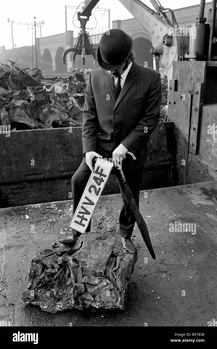Insolito/Suit/Bowler cappello: Uomo sfridi Jaguar auto: D'altro canto, direttore delle vendite per il sig. Graham Parkes, chi dice che non può più permettersi di eseguire il suo 15 miglia per gallone Jaguar, e era disgustato presso i concessionari' offre, ha deciso di guardare la sua distruzione. Febbraio 1975 75-01164-002-003 Foto Stock