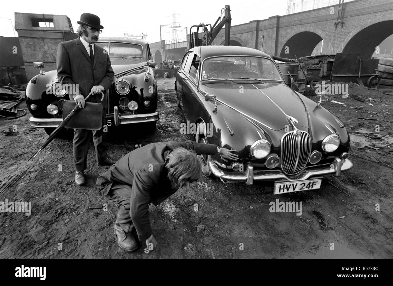 Insolito/Suit/Bowler cappello: Uomo sfridi Jaguar auto: D'altro canto, direttore delle vendite per il sig. Graham Parkes, chi dice che non può più permettersi di eseguire il suo 15 miglia per gallone Jaguar, e era disgustato presso i concessionari' offre, ha deciso di guardare la sua distruzione. Febbraio 1975 75-01164-002-006 Foto Stock