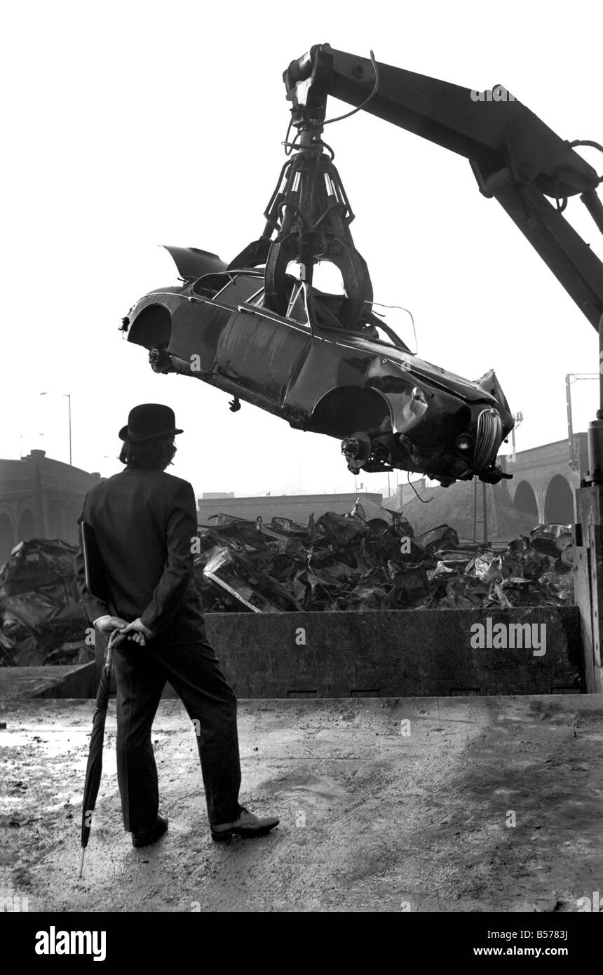 Insolito/Suit/Bowler cappello: Uomo sfridi Jaguar auto: D'altro canto, direttore delle vendite per il sig. Graham Parkes, chi dice che non può più permettersi di eseguire il suo 15 miglia per gallone Jaguar, e era disgustato presso i concessionari' offre, ha deciso di guardare la sua distruzione. Febbraio 1975 75-01164-002-009 Foto Stock