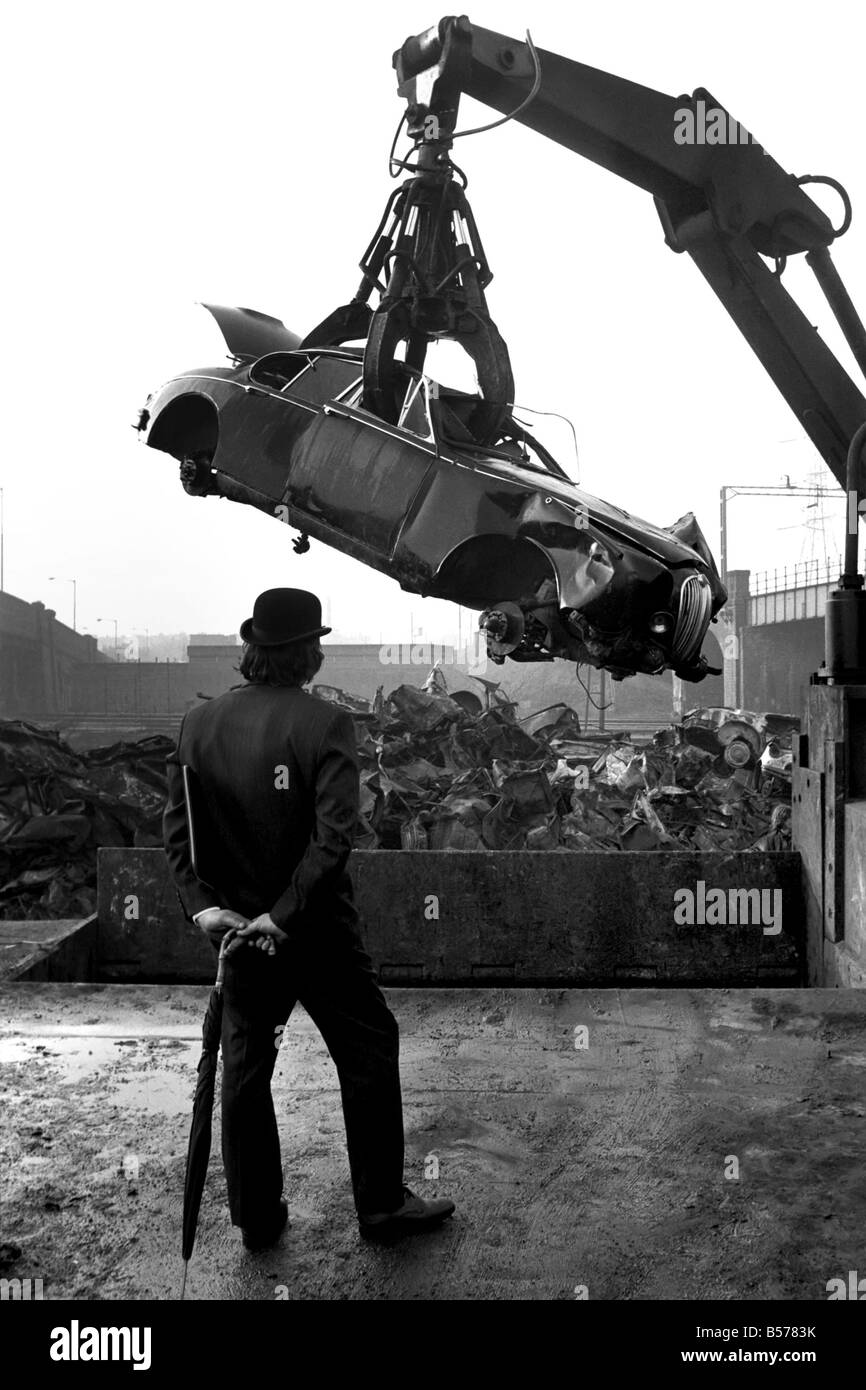 Insolito/Suit/Bowler cappello: Uomo sfridi Jaguar auto: D'altro canto, direttore delle vendite per il sig. Graham Parkes, chi dice che non può più permettersi di eseguire il suo 15 miglia per gallone Jaguar, e era disgustato presso i concessionari' offre, ha deciso di guardare la sua distruzione. Febbraio 1975 75-01164-002-010 Foto Stock