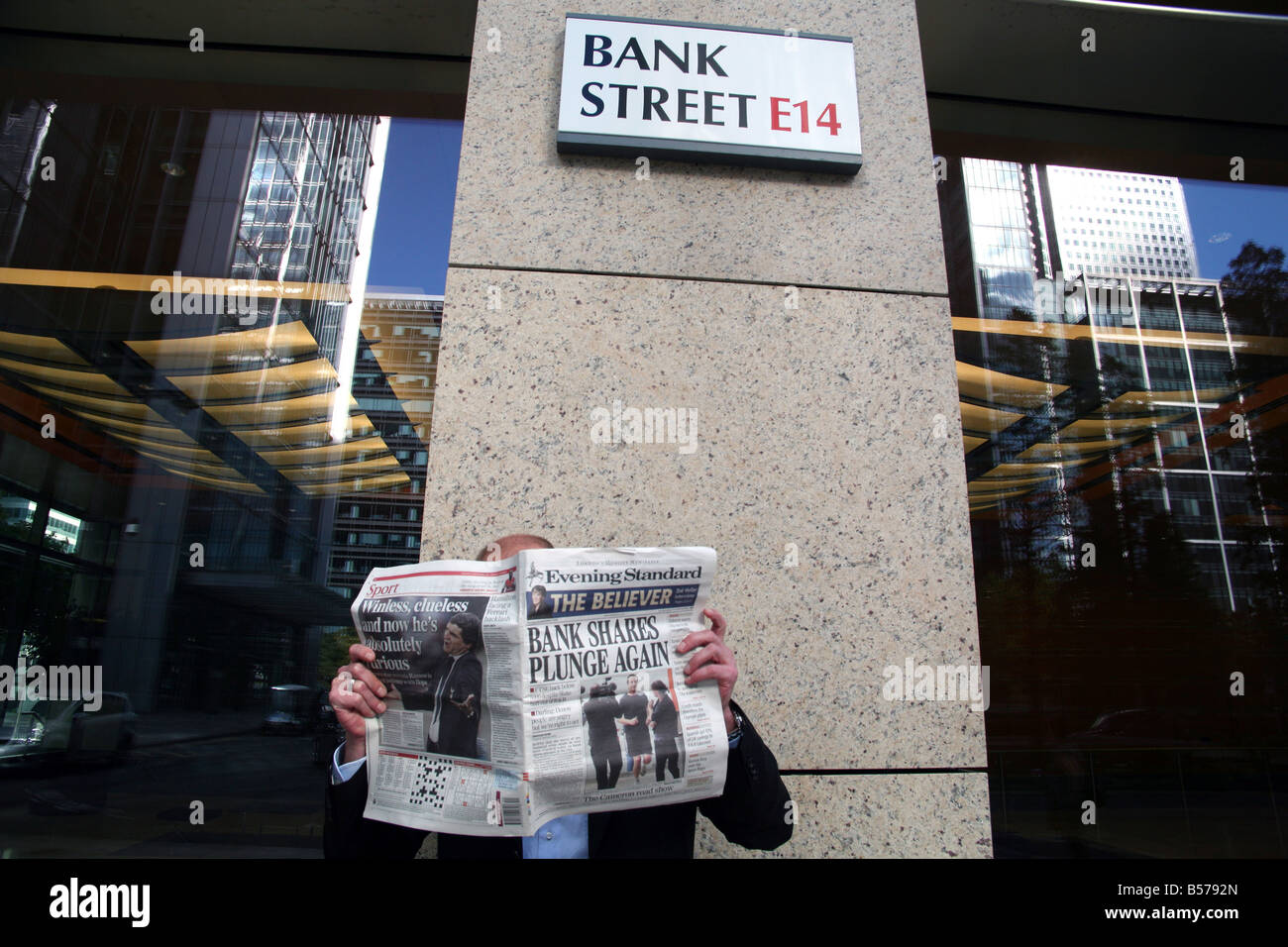 Lavoratore in Bank Street, Canary Wharf, London legge ultime cupo notizie finanziarie Foto Stock