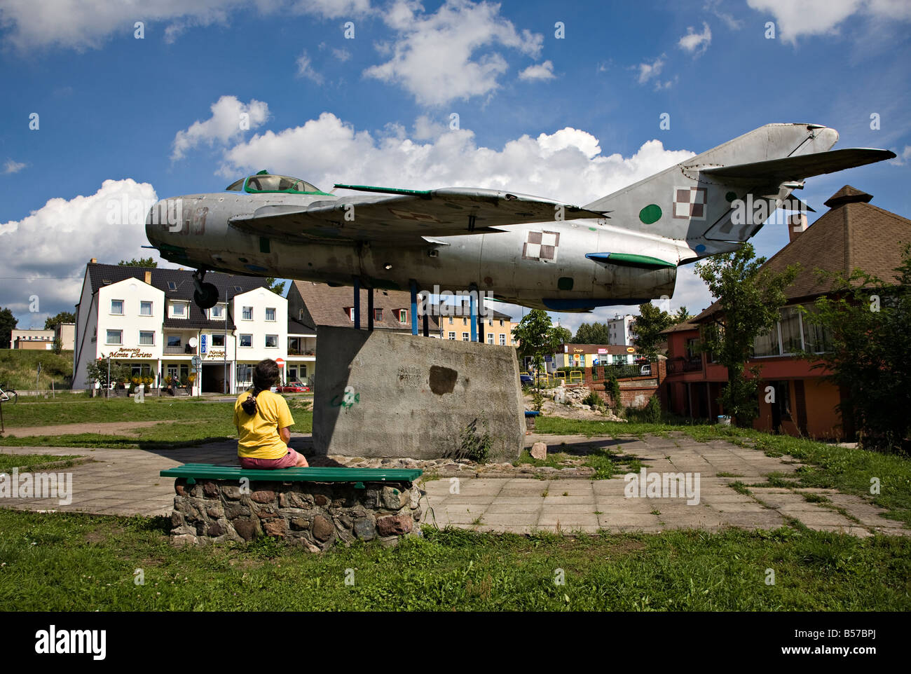 Donna seduta alla ricerca presso il memorial fatta con obsoleti Mig 17 jet fighter aircraft Miastko Polonia Foto Stock