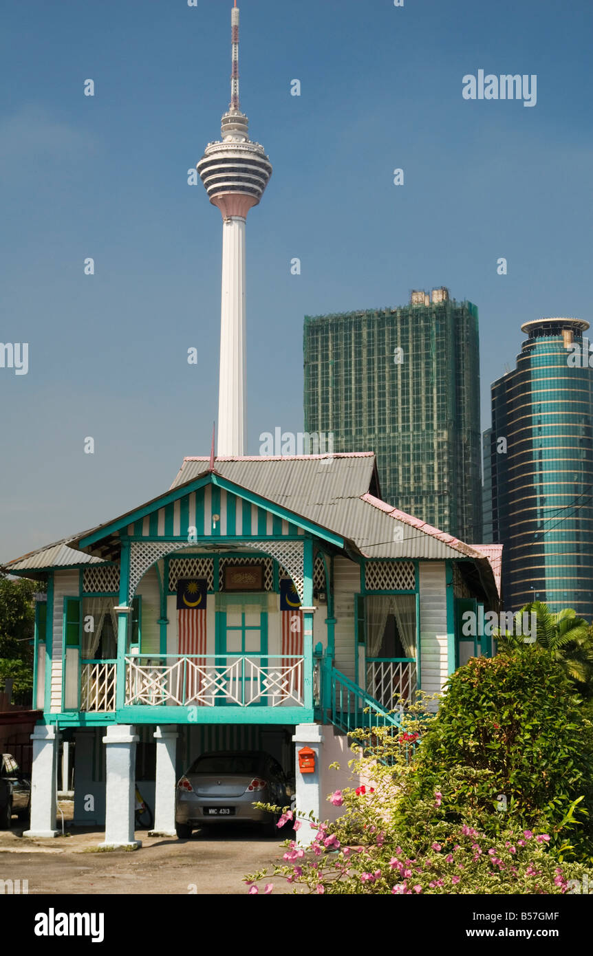 Il vecchio e il nuovo in Malesia - un legno colorato Kampung Baru casa malese su palafitte siede sotto imponenti grattacieli di Kuala Lumpur in Malesia Foto Stock