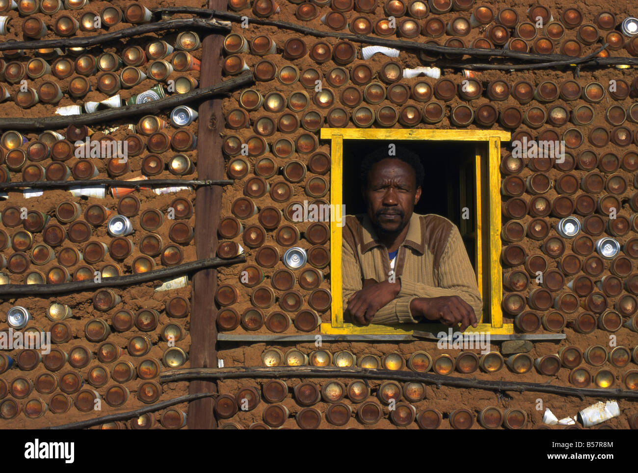 Un negoziante alla finestra del suo edificio che è stato costruito da lattine di bevande, legno e fango, Lesotho Africa meridionale. Foto Stock