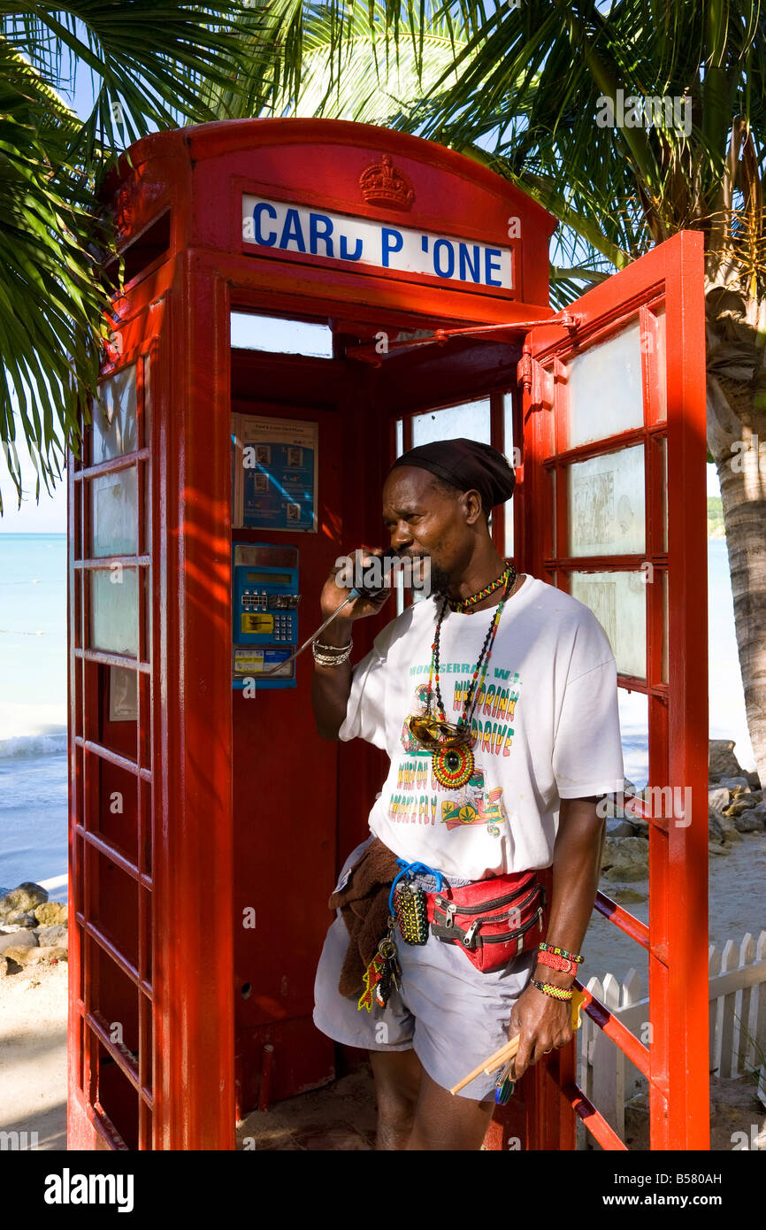 Inglese tradizionale telefono rosso box sulla spiaggia di Dickenson Bay, Antigua, Isole Sottovento, West Indies, dei Caraibi Foto Stock