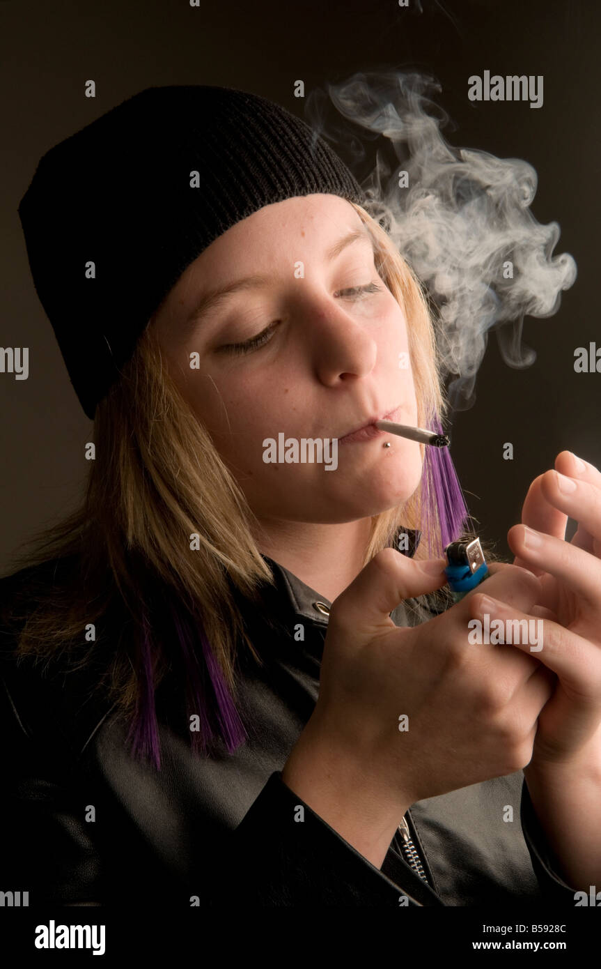 Teenage giovane donna vestita di nero beanie hat fumare una mano sigaretta arrotolata REGNO UNITO Foto Stock