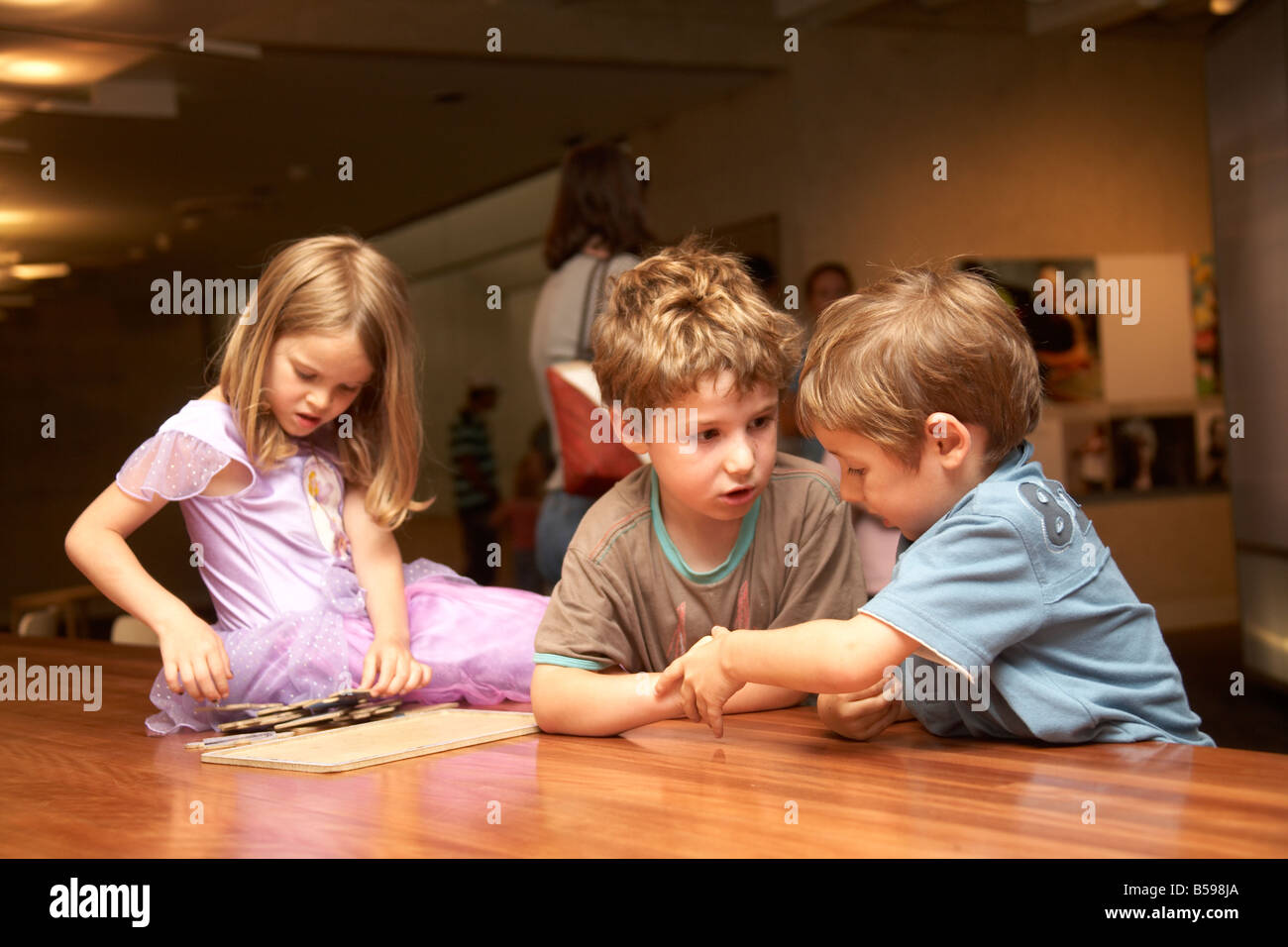 Tre bambini i bambini seduti su una tabella all'interno di un edificio in Brisbane Queensland QLD Australia Foto Stock