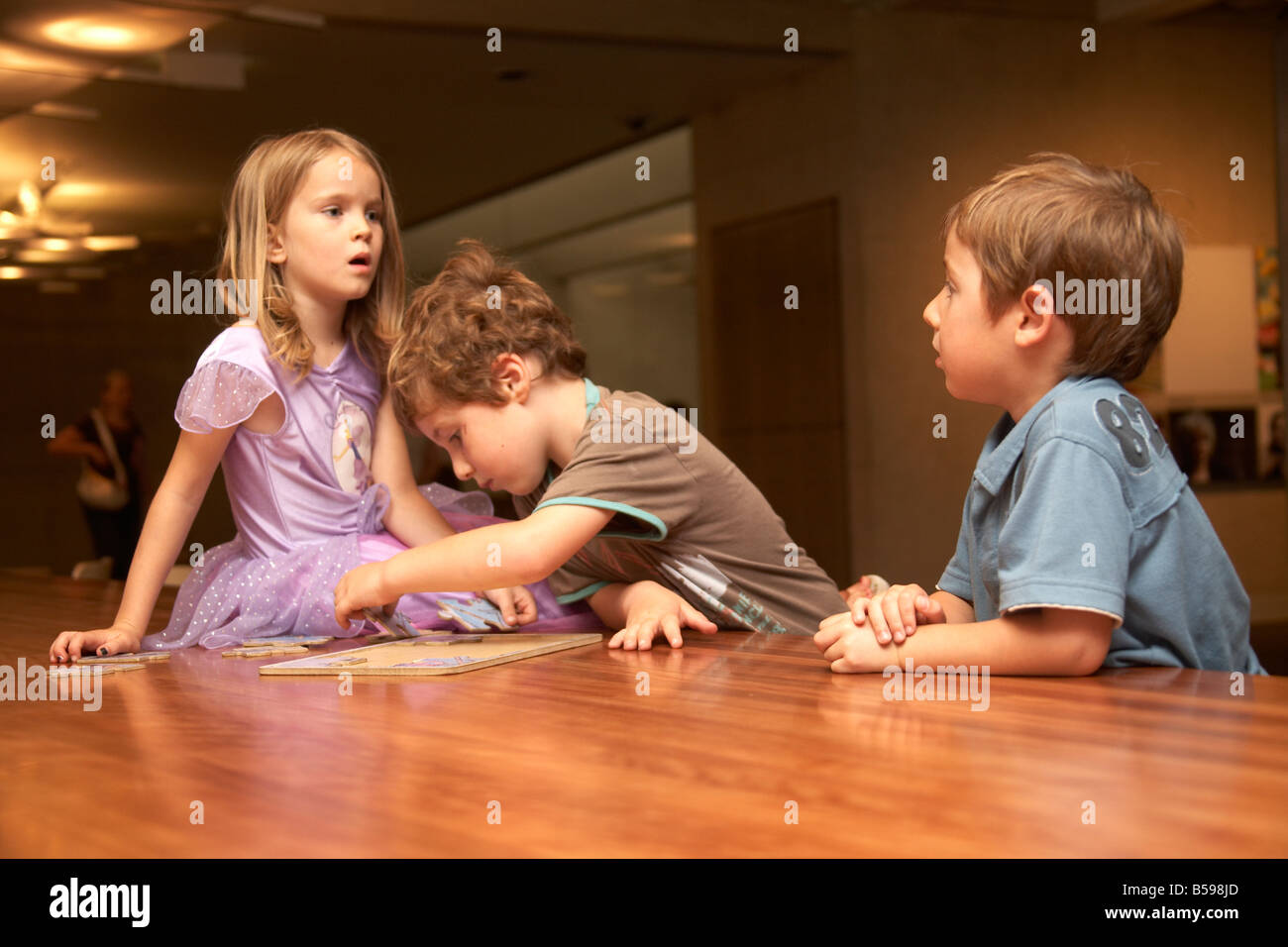 Tre bambini i bambini seduti su una tabella all'interno di un edificio in Brisbane Queensland QLD Australia Foto Stock