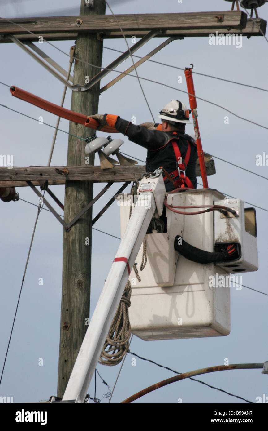 Lavoratore di utility di riparazione di linee di alimentazione dopo un incidente in cui un carrello danneggiato le linee. Foto Stock