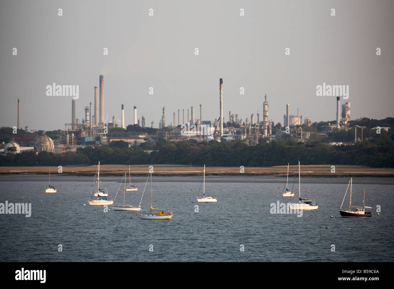 Fawley raffineria di petrolio e di gas naturale del terminale e deposito serbatoi vicino a Hythe con barche a vela su acqua di Southampton Inghilterra Foto Stock