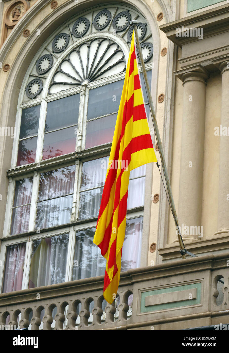 Il giallo e il rosso striato bandiera della Catalogna a volare su un balcone al di fuori di una finestra ad arco a Barcellona, Spagna Foto Stock