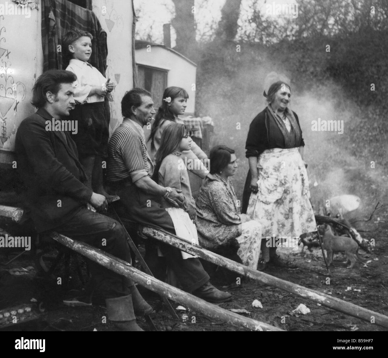 Zingari si riuniscono intorno al fuoco di campo a Corfe Mullen sito con la sig.ra Caroline Warren (seduto). Dicembre 1961 P007197 Foto Stock