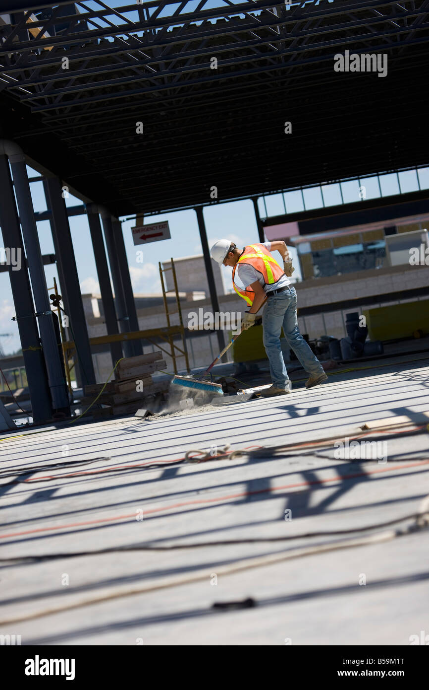 Spazzamento lavoratore presso un sito in costruzione Foto Stock