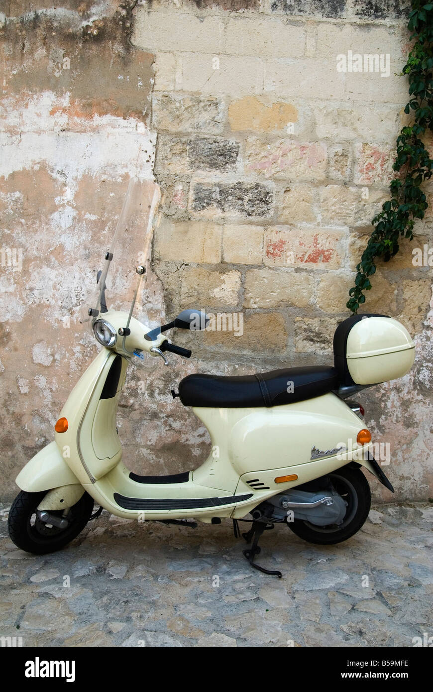 Una in stile retrò Piaggio scooter Vespa parcheggiata di fronte ad una parete spiovente su una strada basolata a Matera, Basilicata, Italia Foto Stock