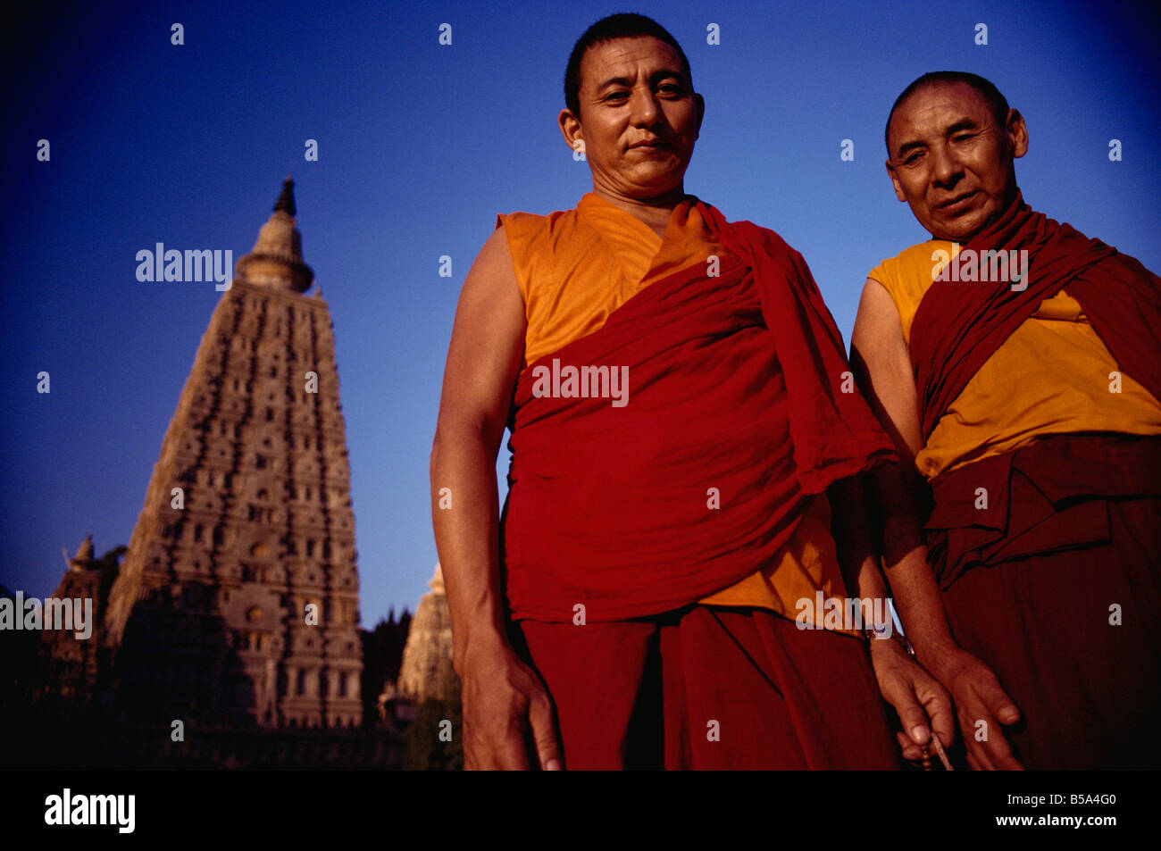 Due monaci tibetani con il principale tempio di Mahabodhi in background Bodh Gaya stato del Bihar India Asia Foto Stock