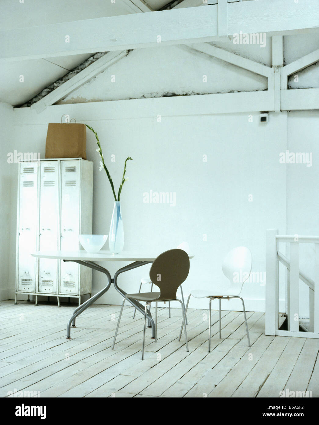 In bianco e nero di Arne Jacobsen Ant e sedie in metallo circolare nella tabella di conversione loft sala da pranzo con dipinto di bianco con pavimento in legno Foto Stock