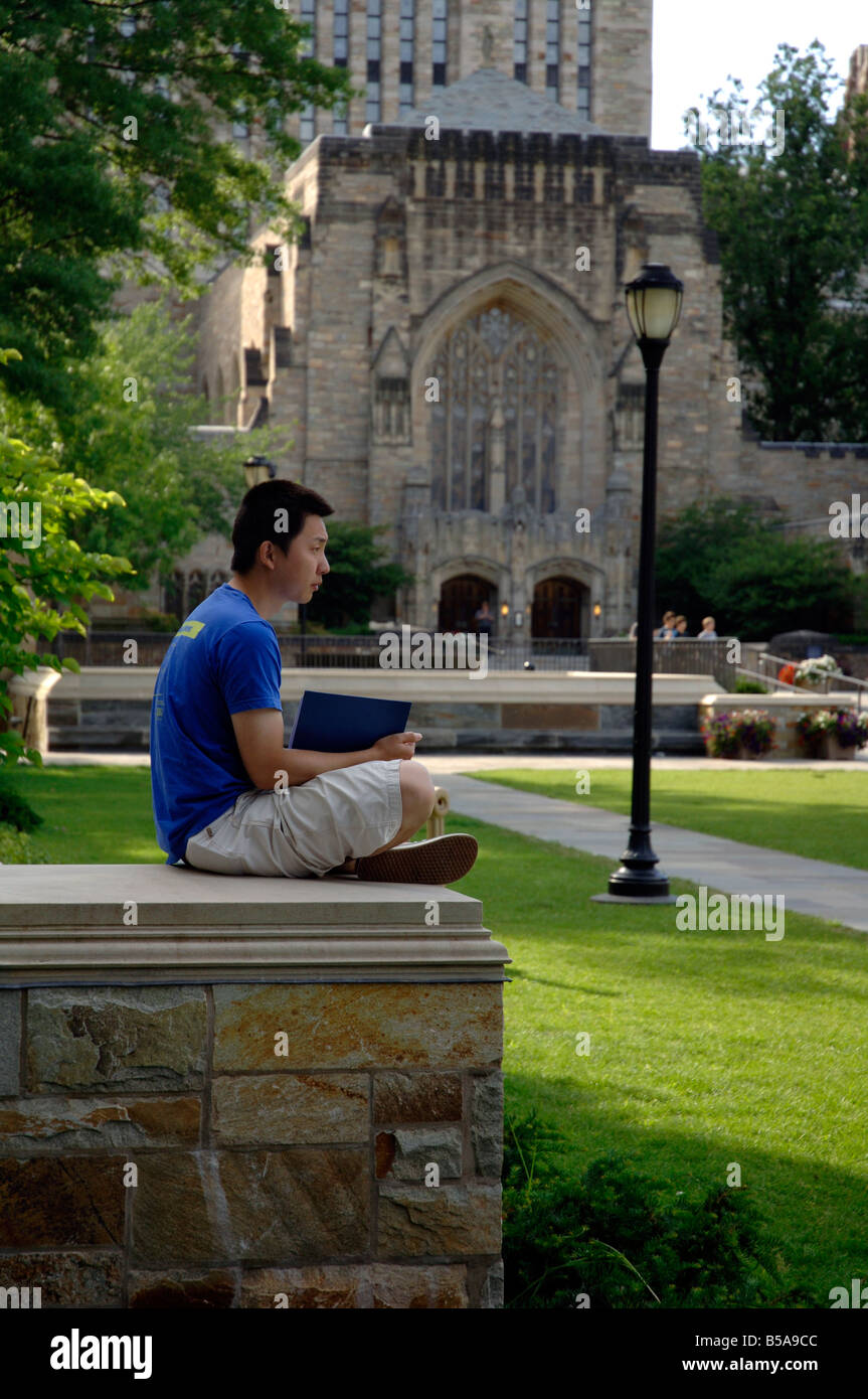 Asian studente lettura sul campus di Yale con Sterling Library in background. Foto Stock