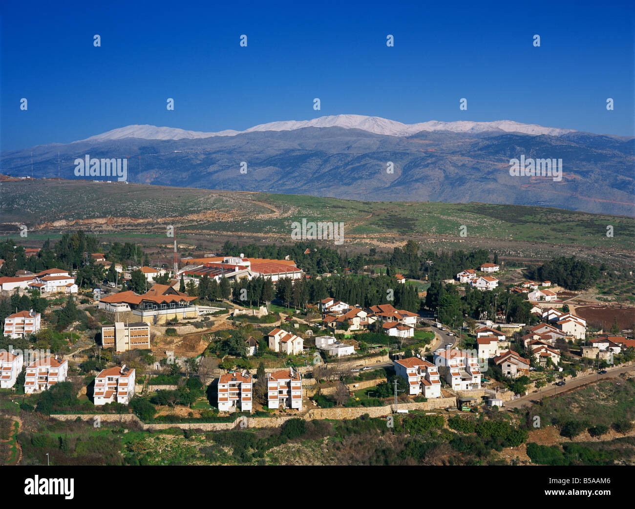 Case e stadium nella città di Metula nella Galilea superiore, con coperta di neve Monte Hermon in background, Israele, Medio Oriente Foto Stock