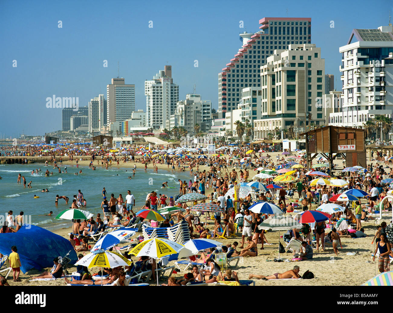 La folla di turisti sulla spiaggia con alti edifici sul lungomare, a Tel Aviv, Israele, Medio Oriente Foto Stock